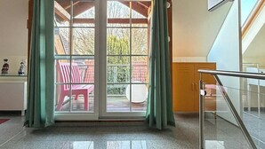 Een hotel lobby met een kleurrijk tapijt, een schuifdeur naar een buitenruimte en een trap.