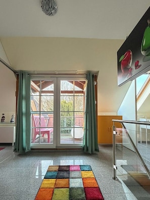 A hotel lobby with a colorful rug, a sliding glass door leading to an outdoor area, and a staircase.