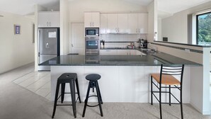 Una cocina moderna con una isla central, electrodomésticos de acero inoxidable y vistas a zonas verdes.
