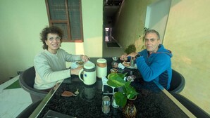 A dining area with a table set for two, a coffee maker, a plant, and a vase. - Orchha best homestay (Orchha)