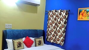 A neatly made bed with a floral bedspread, a blue headboard, and a ceiling fan. - Orchha best homestay (Orchha)