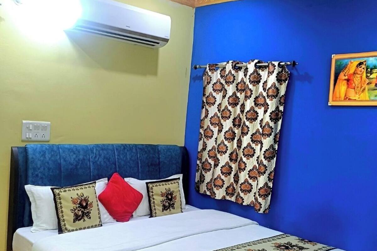 A neatly made bed with a floral bedspread, a blue headboard, and a ceiling fan.