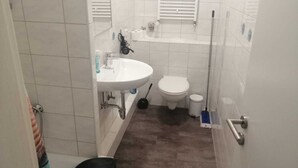 Une petite salle de bain avec un lavabo blanc, des toilettes et un espace douche.