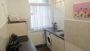 Une cuisine compacte équipée d’un lave-linge, d’un four à micro-ondes et d’une fenêtre avec des rideaux.