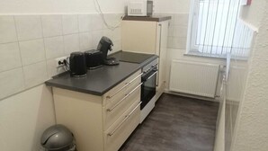 Une cuisine compacte équipée d’une cuisinière, d’un four à micro-ondes et d’une machine à café, le tout installé sur le plan de travail.