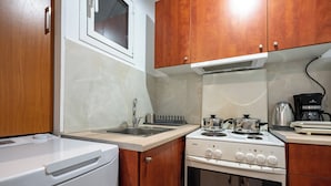 A compact kitchen with wooden cabinets, a white stove, a sink, and a coffee maker.