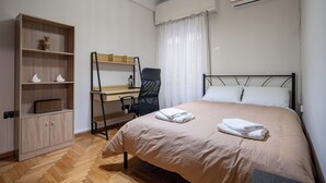 A neatly arranged bedroom with a bed, a desk, a chair, and a wardrobe.