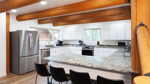 A modern kitchen with a large island, stainless steel appliances, and wooden ceiling beams. - Almost Heaven - Newly Built! - In Town - On the River - WiFi - Grill - Mountain (Red River)