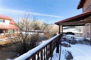 Una terraza de madera con suelo cubierto de nieve y vistas a un paisaje montañoso.