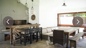 A rustic dining area with a wooden table and chairs, a sofa, and a stone floor.