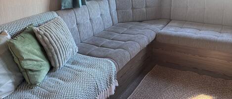 A cozy living room with a sectional sofa, a patterned throw blanket, and a rug.