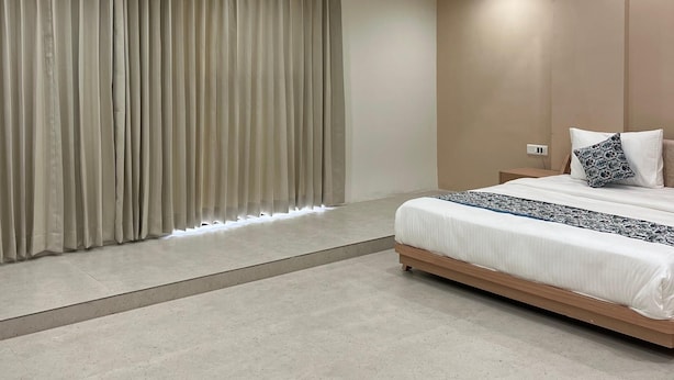 Ein modernes Schlafzimmer mit einem großen Bett, einem Deckenventilator, Einbauleuchten und einem großen Fenster mit Vorhängen.