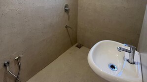Ein kleines Badezimmer mit Fliesen, einer Dusche, einem Fenster und einem Waschbecken.