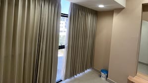 Ein Zimmer mit beigen Wänden, einer hölzernen Bank und einem Fenster mit beigen Vorhängen.