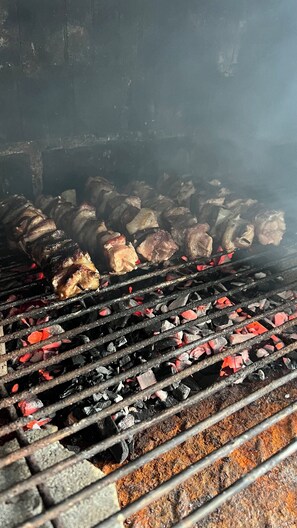 Uma churrasqueira com carne assando sobre carvão.