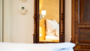 Et hotelværelse med en seng med træstel, en sengebordlampe og et spejl der reflekterer rummet.