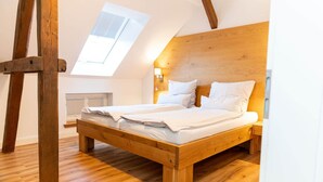 A wooden bed in a room with a sloped ceiling and a skylight. - Graf Enno | Cozy Two-Level Apartment | North Sea (Norden)