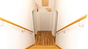 A wooden staircase with white walls and a wooden floor leading to a door. - Graf Enno | Cozy Two-Level Apartment | North Sea (Norden)