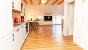 Eine geräumige Küche mit Holzboden, weißen Schränken und einem integrierten Fernseher.