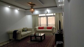 Uma sala de estar com sofá, mesa de centro e televisão.