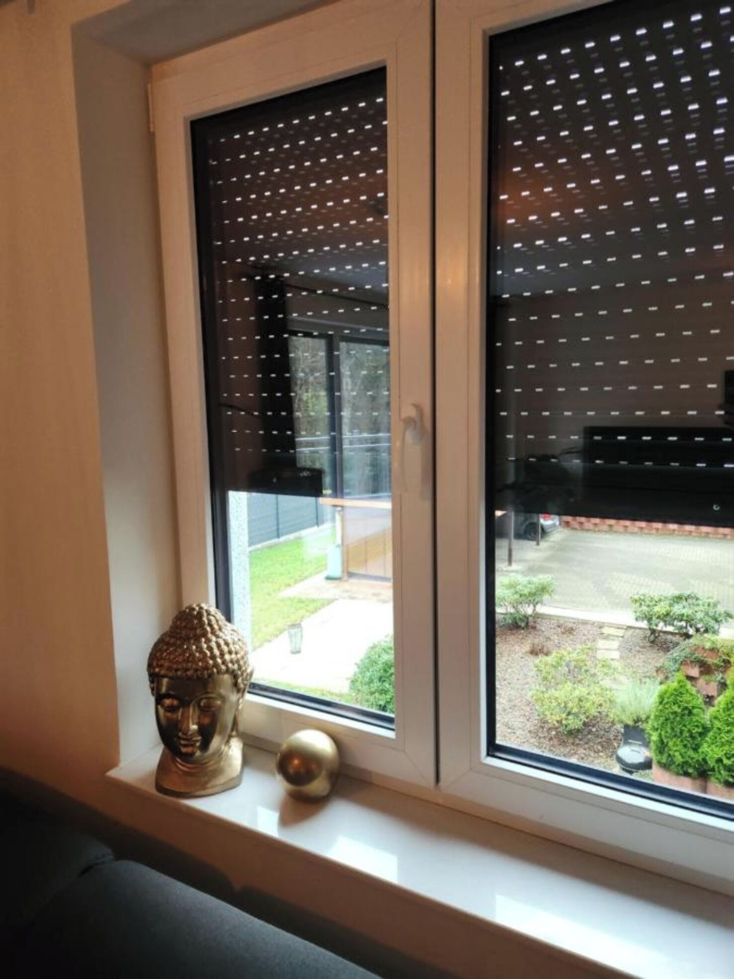 A window with a decorative screen and a Buddha statue on the sill.