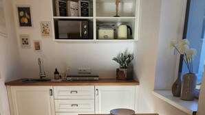 A modern kitchen with white cabinetry, a wooden countertop, and a dining table set for two.