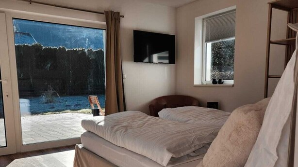 A bedroom with a bed, a TV, a window, and a view of a snowy landscape.