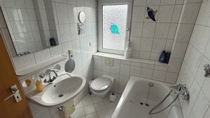 A modern bathroom with a sink, toilet, and bathtub. - Apartment in Troisdorf T06 (Troisdorf)