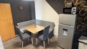 A compact kitchenette with a microwave, refrigerator, and a small table with chairs. - Apartment in Troisdorf T06 (Troisdorf)