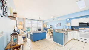 A modern kitchen with a blue accent wall, a dining area with a view, and a cozy living space with a blue sofa.