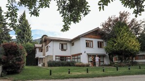 A two-story house with a stone facade, wooden trim, and a sloped roof. - Hostería & Apart Hotel Carelhue (San Carlos de Bariloche)
