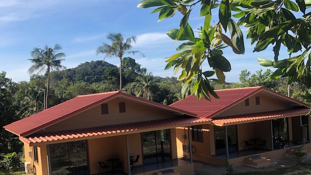 Un edificio de dos pisos con techo rojo, ventanas grandes y un patio cubierto.