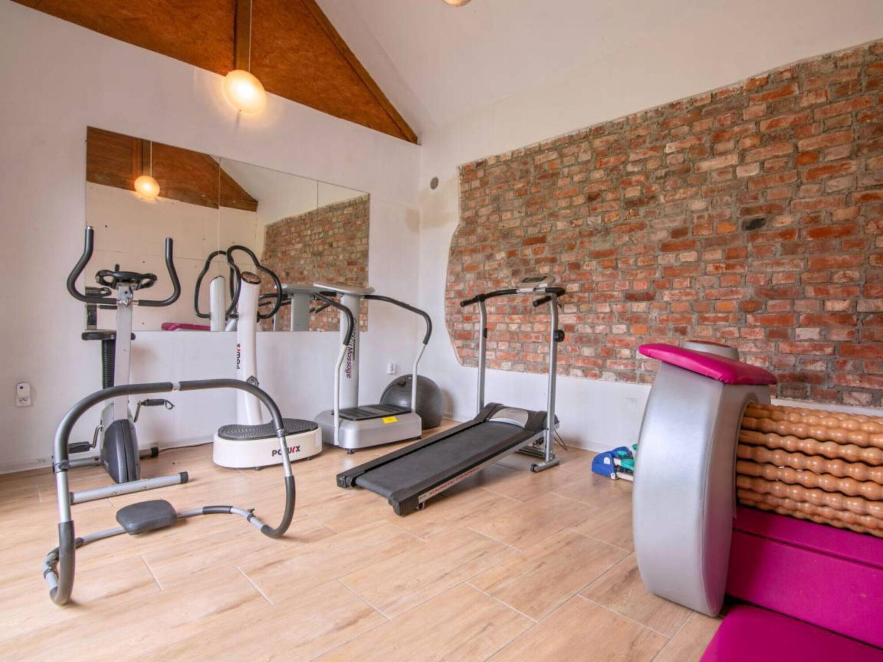 Gimnasio en casa con equipo de ejercicio, incluyendo una cinta de correr, elíptica y máquina de pesas.