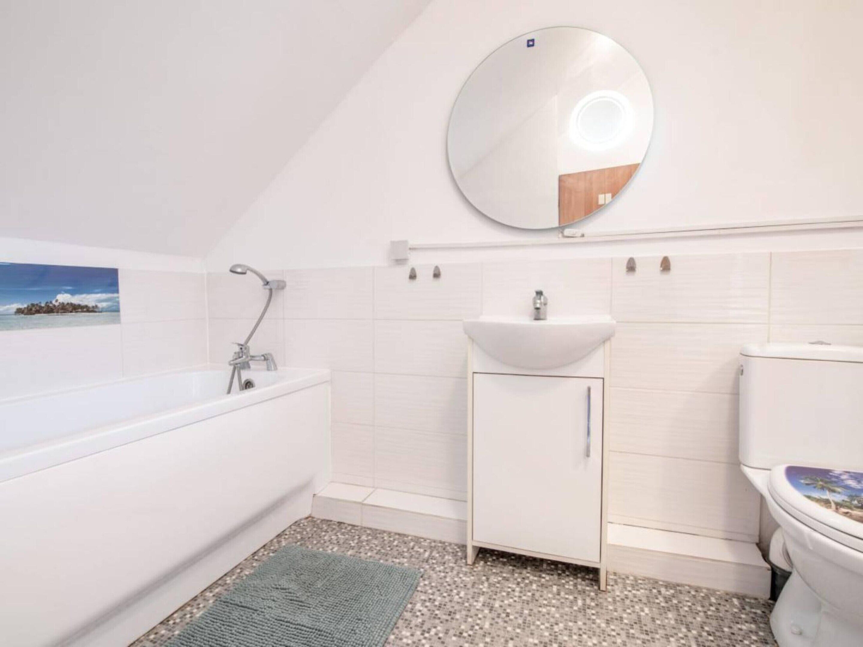 Ein Badezimmer mit Badewanne, Waschbecken, Toilette und Spiegel.