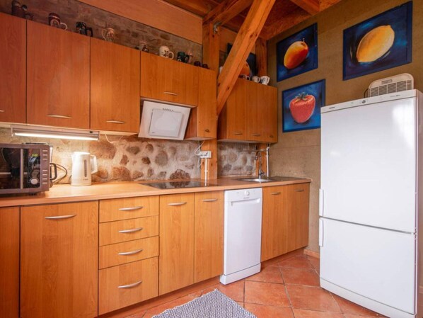 A kitchen with wooden cabinets, a microwave, a coffee maker, a dishwasher, and a refrigerator. - Atmospheric Holiday Home With a Swimming Pool (gmina Dobra)
