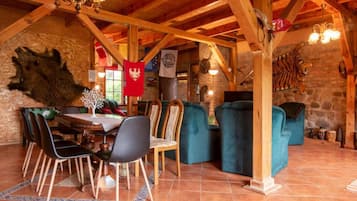 Un comedor rústico con mesa de madera, sillas y una araña.