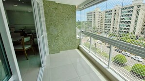 Een balkon met uitzicht op een parkeerplaats en gebouwen.