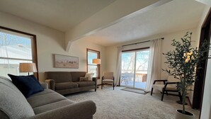A living room with a sofa, armchair, and a potted plant. - Clean and Cozy Lakefront cabin on Ida Lake (Monticello)