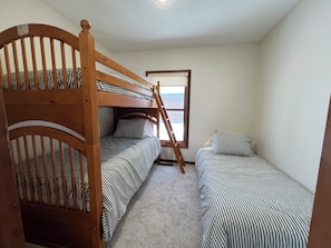 A room with two bunk beds, a window, and a door.