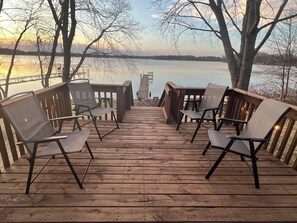 Une terrasse en bois, agrémentée de chaises et de tables, qui offre une vue sur une étendue d’eau.
