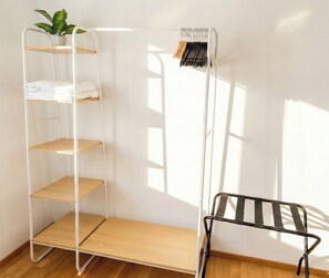 Une pièce avec une étagère métallique blanche, un présentoir noir et une plante en pot.