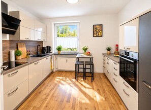 Une cuisine moderne avec une fenêtre, un plancher en bois et des appareils électroménagers intégrés.
