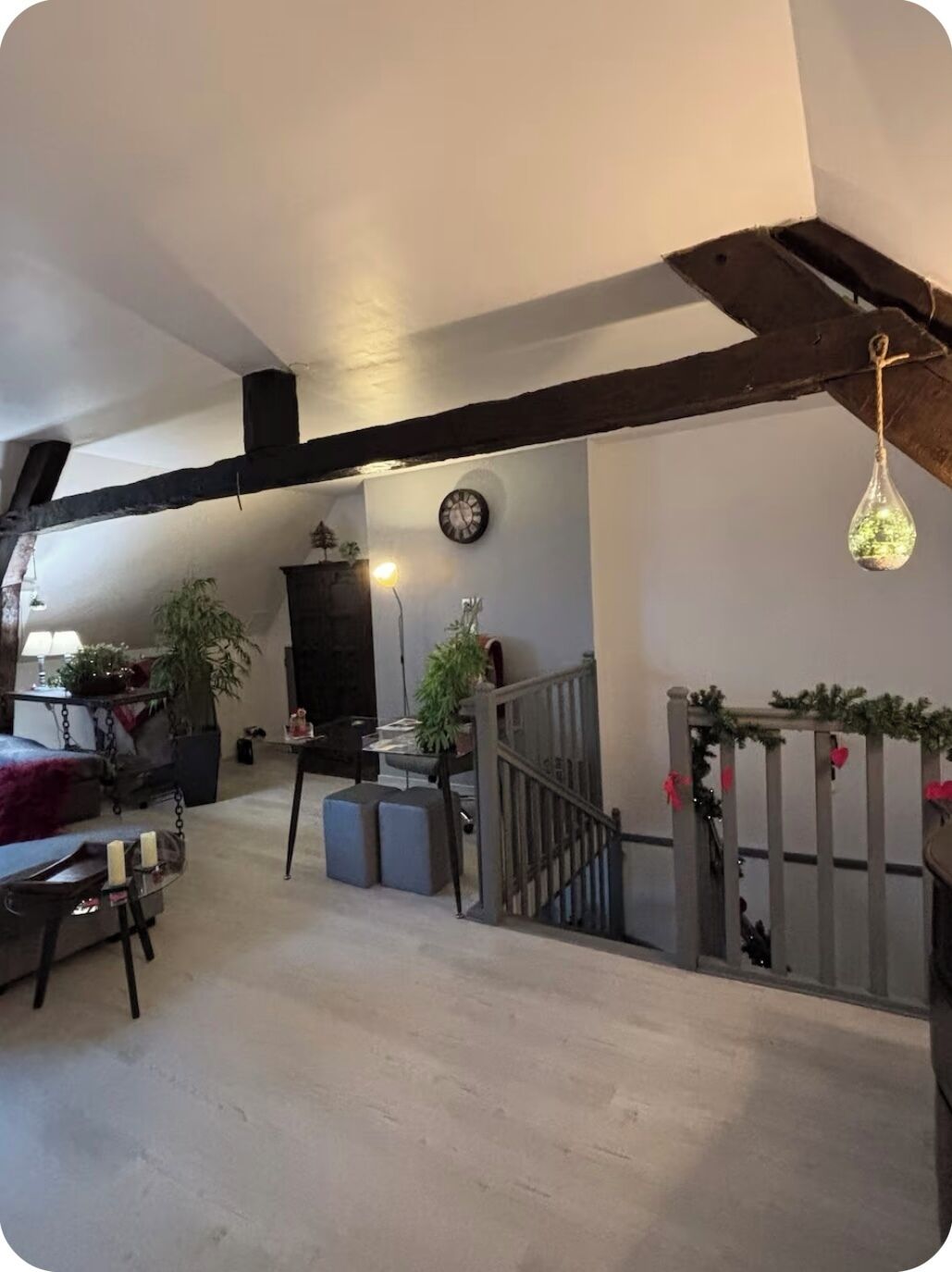 Un vaste espace de vie doté d’un haut plafond, de poutres apparentes, d’un escalier et d’un coin repas.