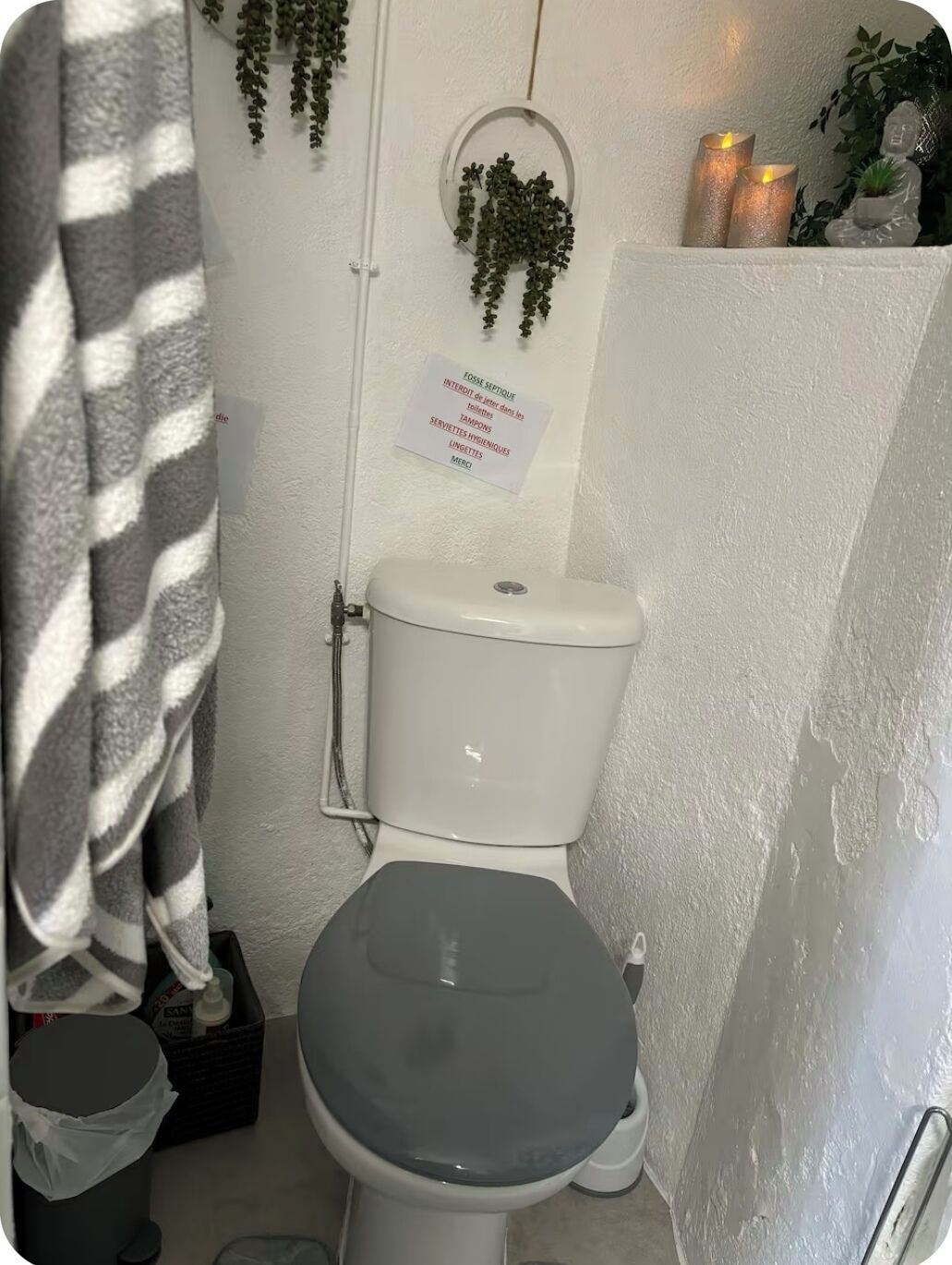 Ein kleines, kompaktes Badezimmer mit Toilette, Duschvorhang und einem Schild auf Französisch.