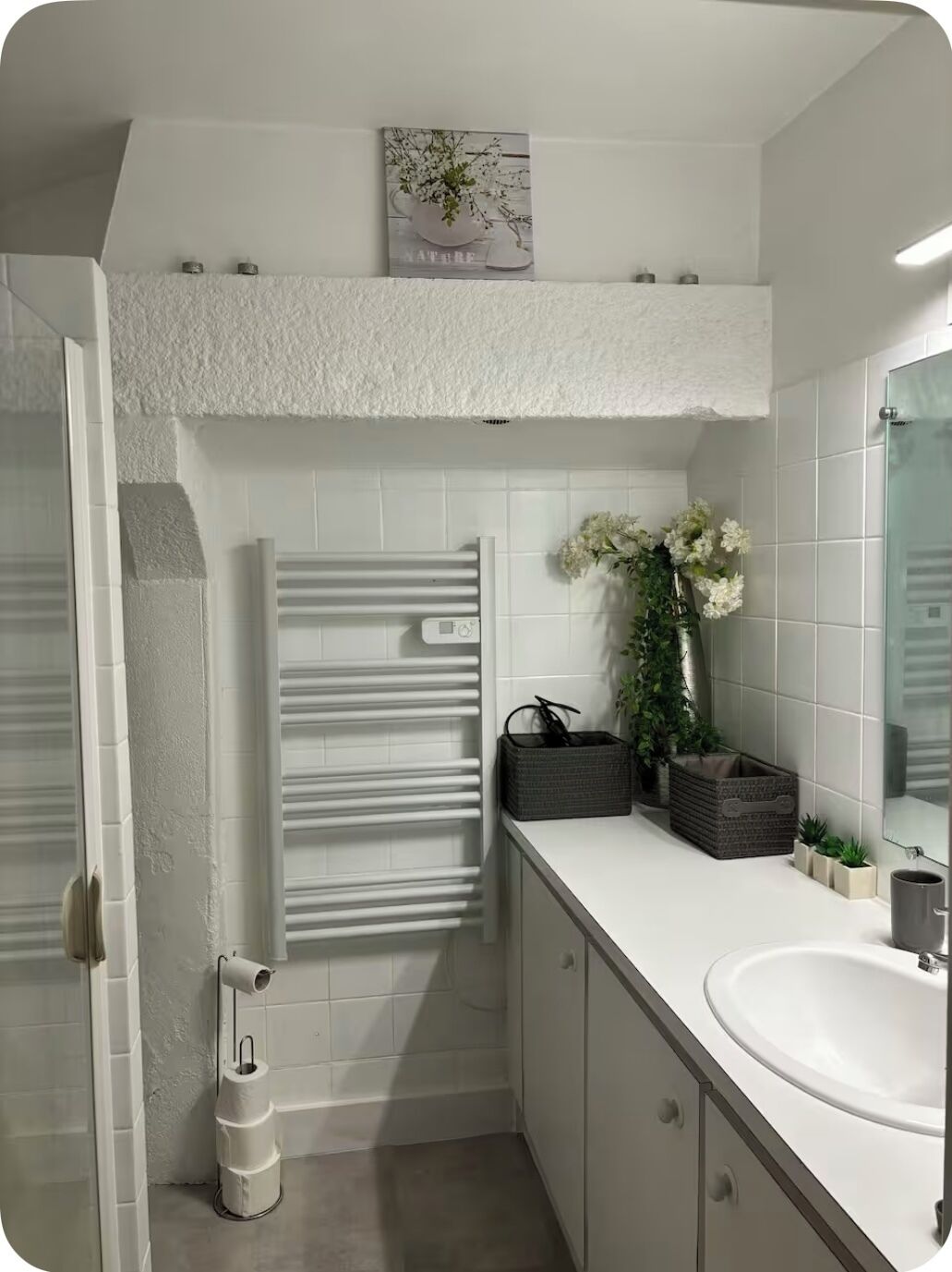 Ein modernes Badezimmer mit einem weißen Waschbecken, einem Spiegel, einem Handtuchhalter und einem Toilettenpapierhalter.