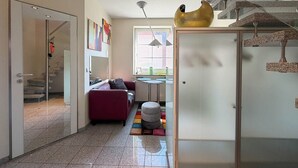 Een modern interieur met een trap, een bank, een bijzettafeltje en een kleurrijk vloerkleed.