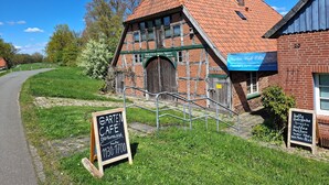 Een traditioneel gebouw met een schuin dak, een houten deur en een bordje waarop een café staat.