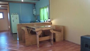Una mesa de comedor de madera en una habitación con una cocina al fondo.