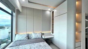 Een moderne slaapkamer met een groot bed, een inbouwkast en uitzicht op de stad.
