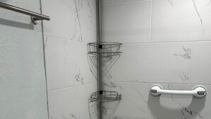 Een douche met een metalen rek, een handgreep en een klein houten krukje.